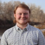 Picture of Elliott smiling outdoors, wearing a light patterned shirt